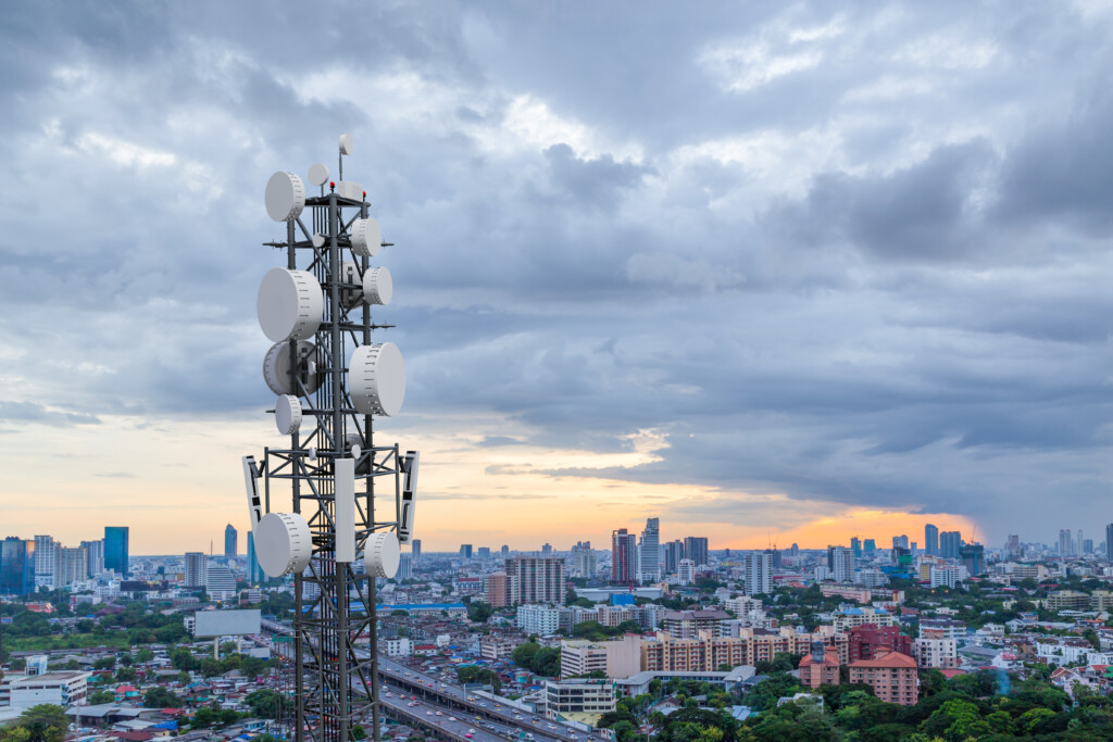 Telecommunication tower with 5G cellular network antenna on city background. Image by Adobe Stock