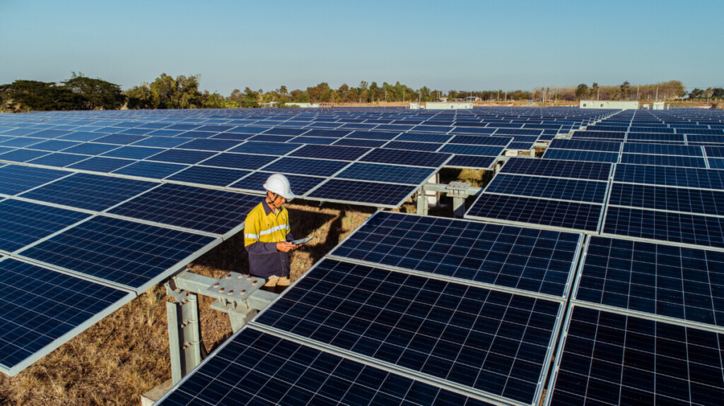 Technician and investor walking in Solar energy Farm through field of solar panels checking the panels at solar energy installation.Solar cells will be an important renewable energy of the future.